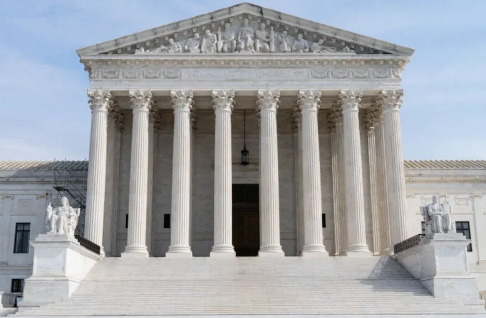 The United States Supreme Court building with its grand columns and statues at the entrance.