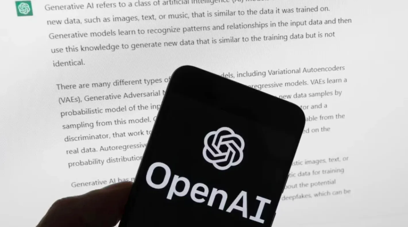 A person holding a smartphone in front of a computer screen. Text on the screen describes generative AI and mentions OpenAI.